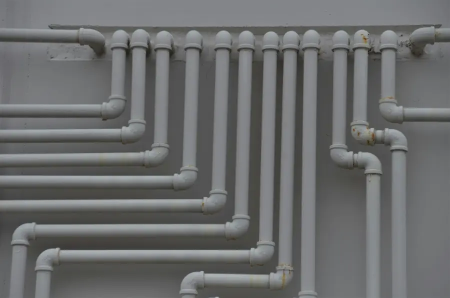 Neatly installed rows of grey supply pipe on a wall