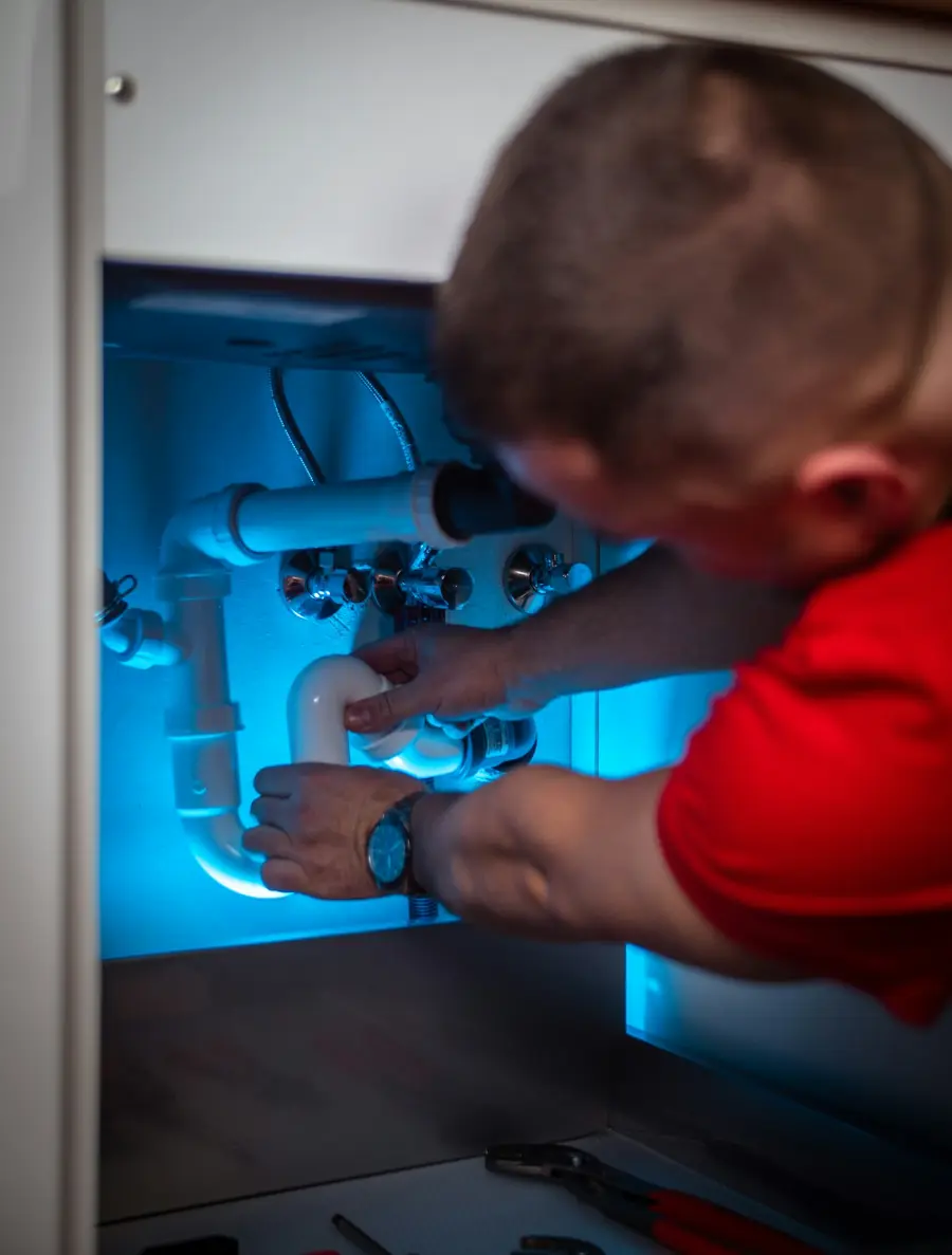 Plumber repairing the drain trap under a bathroom sink
