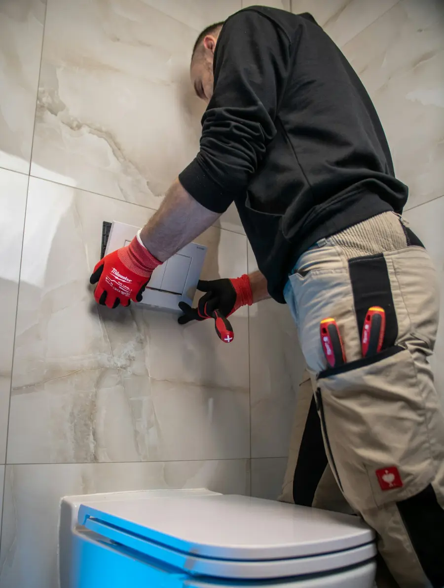 Plumber working on a wall fitting in a tiled bathroom