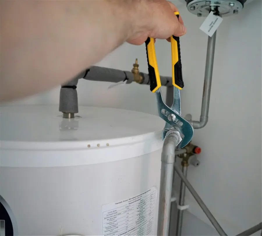 Hand tightening a fitting on a white tank water heater