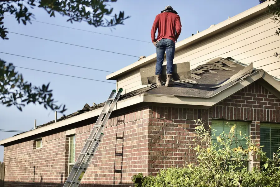 Roofer on a ladder-accessed roof of a brick home