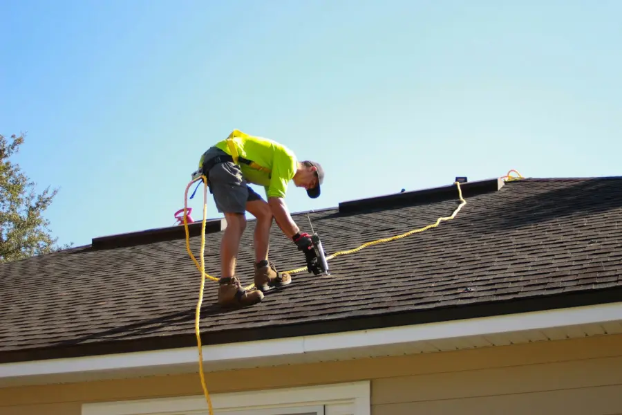 Roofer fastening shingles near the roof edge