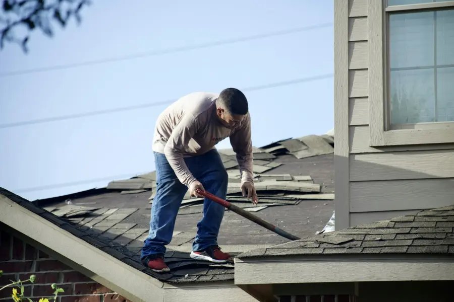 Roofer stripping old shingles from a residential roof